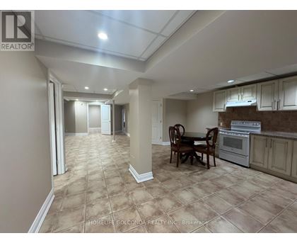 A dining room with a table set for two and a kitchen area in the background.