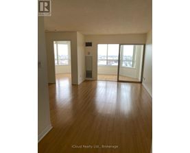 A room with wooden floors and a view of the city through the windows.