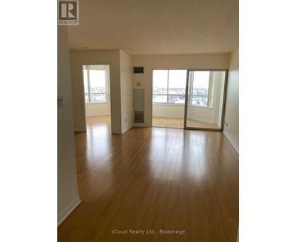 A room with wooden floors and a view of the city through the windows.