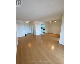 A spacious room with wooden flooring and white walls.
