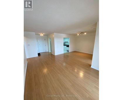 A spacious room with wooden flooring and white walls.