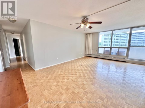 A spacious room with a ceiling fan and large windows.