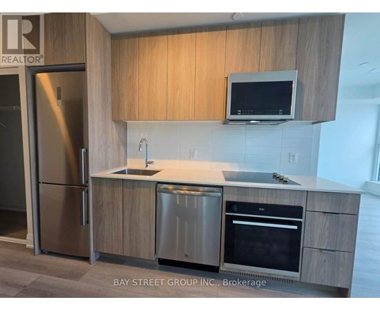 A modern kitchen with a refrigerator, sink, and oven.