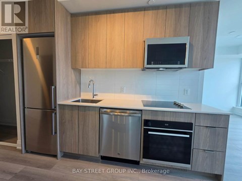 A modern kitchen with a refrigerator, sink, and oven.