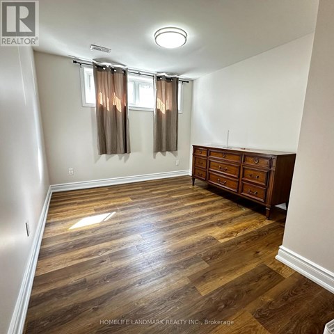 A room with wooden flooring and a dresser with a window.