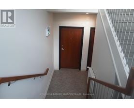 A hallway with a wooden door and a staircase with white railings.