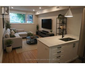 A modern kitchen with a white countertop and a flat screen TV mounted above it.