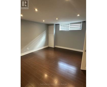 A room with wooden flooring and a window with blinds.