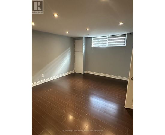 A room with wooden flooring and a window with blinds.