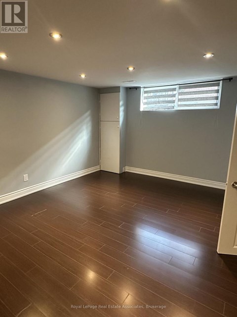 A room with wooden flooring and a window with blinds.