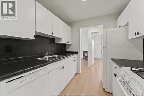 A kitchen with white cabinets and black countertops.