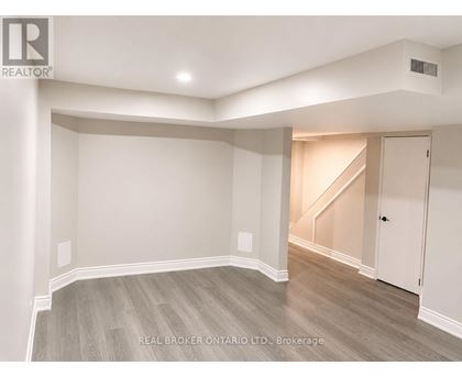 A spacious room with a staircase in the background.