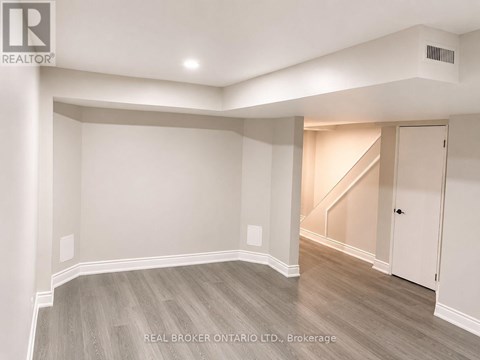 A spacious room with a staircase in the background.