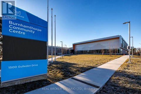 A blue and white sign for the Burnhamthorpe Community Centre stands in front of a modern building.