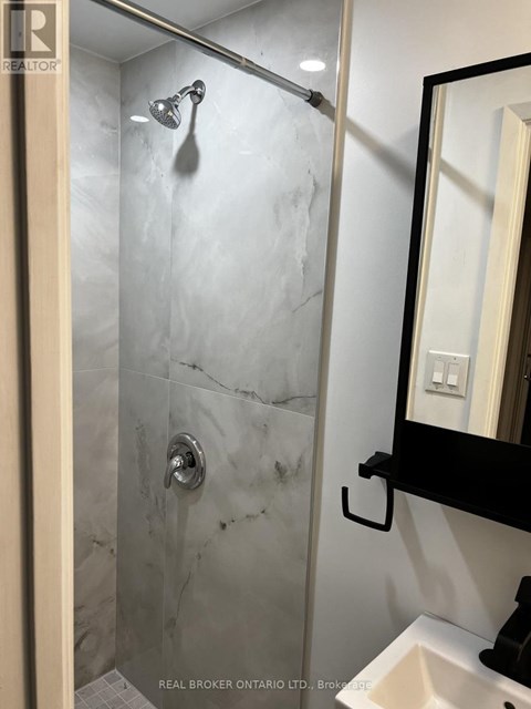 A bathroom with a marble shower and a sink.