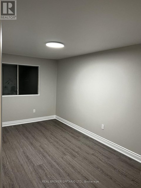 A room with grey flooring and a window with blinds.