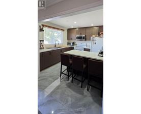 A kitchen with brown chairs and a white fridge.