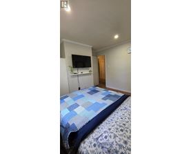 A bed with a blue and white comforter is in the foreground of the image.