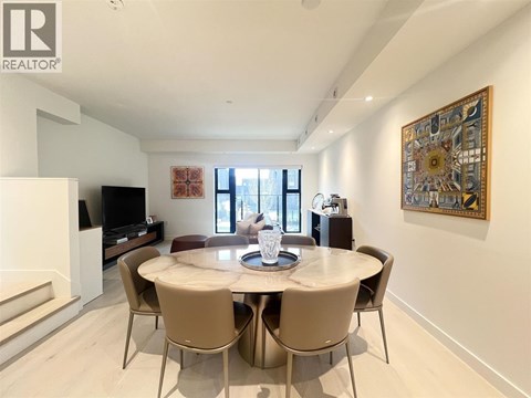 A dining room with a table set for four and a television.
