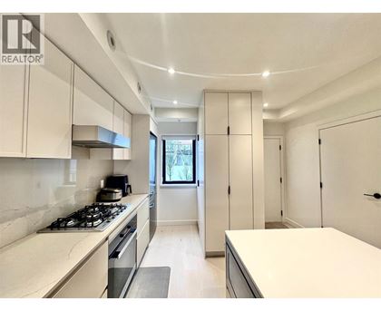 A modern kitchen with white cabinets and a stove top oven.