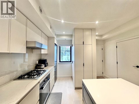 A modern kitchen with white cabinets and a stove top oven.