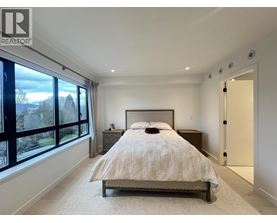 A bedroom with a large bed and a window overlooking a garden.