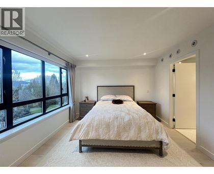 A bedroom with a large bed and a window overlooking a garden.