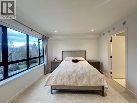 A bedroom with a large bed and a window overlooking a garden.