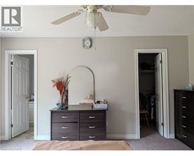 A bedroom with a dresser and a ceiling fan.