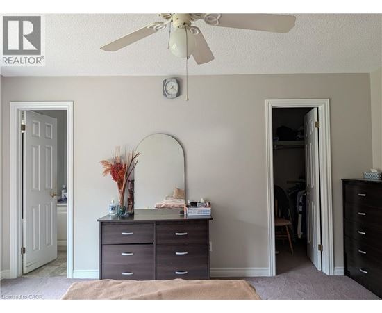 A bedroom with a dresser and a ceiling fan.