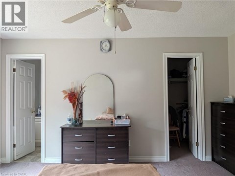 A bedroom with a dresser and a ceiling fan.