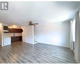 A spacious room with a ceiling fan and a staircase leading to another room.