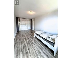 A bedroom with a bed and a wooden floor.