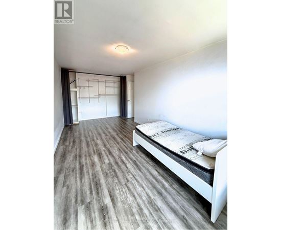 A bedroom with a bed and a wooden floor.