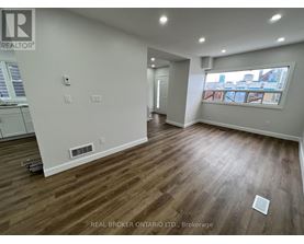 A room with wood flooring and a window overlooking a cityscape.