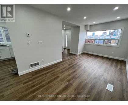 A room with wood flooring and a window overlooking a cityscape.