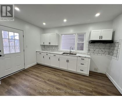 A kitchen with white cabinets and a wooden floor.