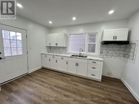 A kitchen with white cabinets and a wooden floor.