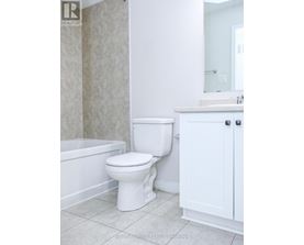 A white toilet in a bathroom with a white cabinet and a white bathtub.