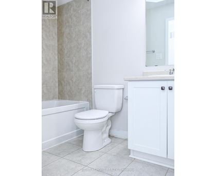 A white toilet in a bathroom with a white cabinet and a white bathtub.