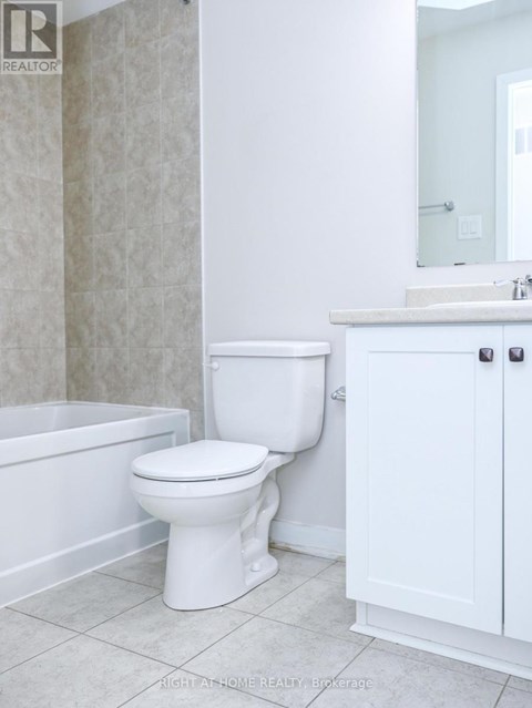 A white toilet in a bathroom with a white cabinet and a white bathtub.