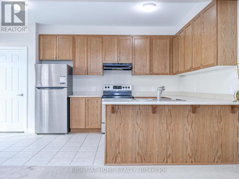 A kitchen with wooden cabinets and a stainless steel refrigerator.