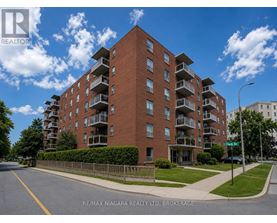 A large red brick apartment building with balconies on the upper floors.