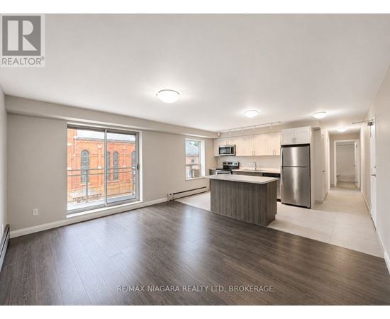 A spacious, empty room with a kitchenette and a refrigerator.