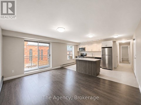 A spacious, empty room with a kitchenette and a refrigerator.