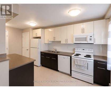 A kitchen with white appliances and brown countertops.