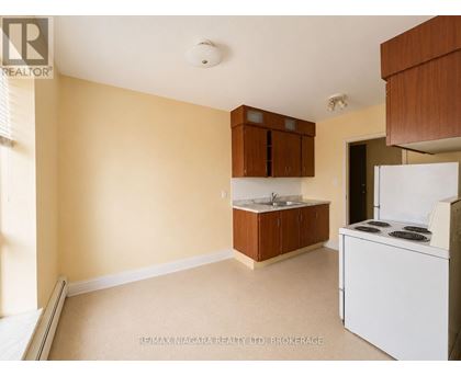 A kitchen area with a white fridge and brown cabinets.