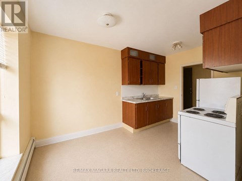 A kitchen area with a white fridge and brown cabinets.