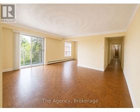 A spacious room with wooden flooring and a long hallway.