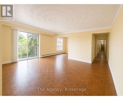A spacious room with wooden flooring and a long hallway.
